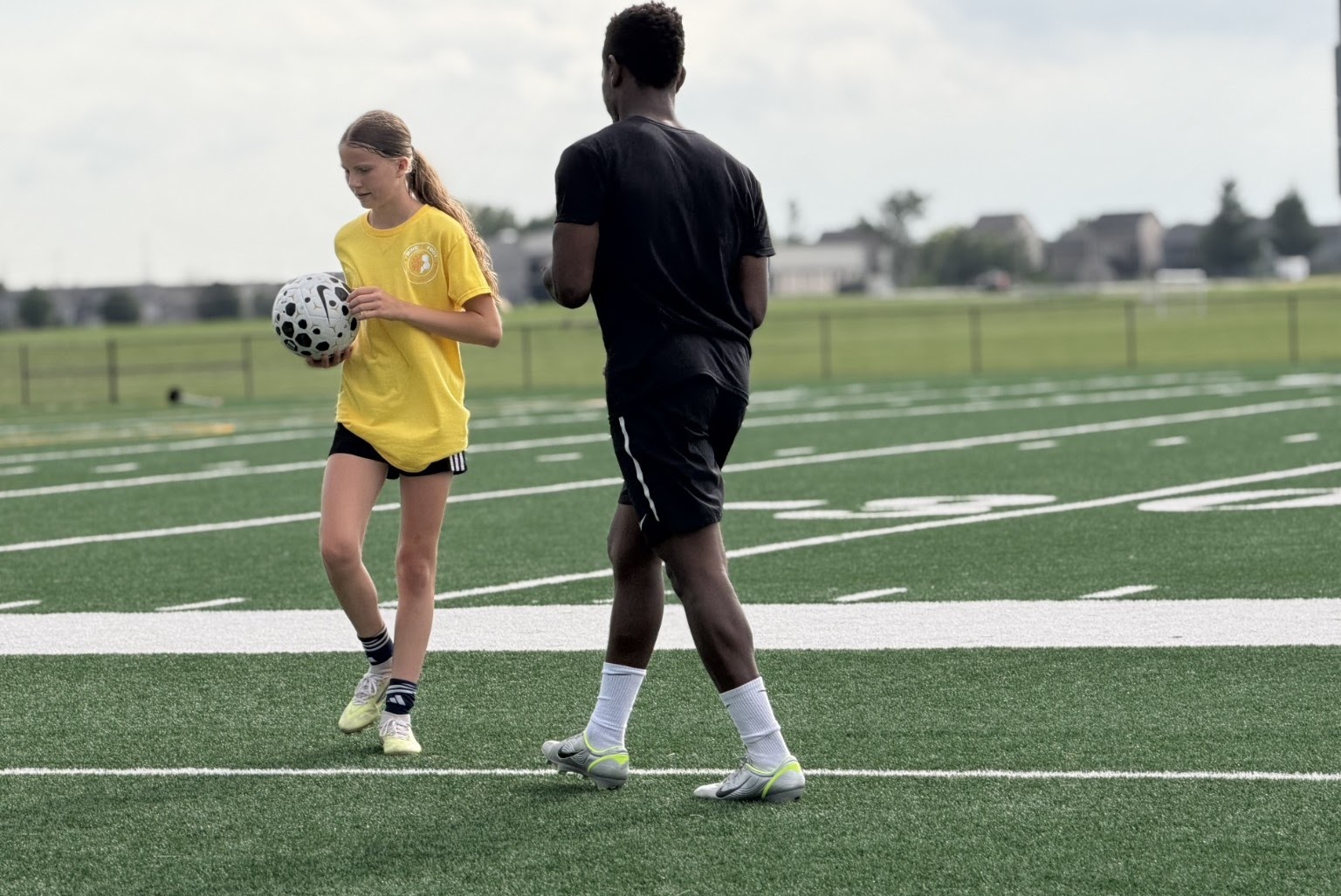 Coach working one-on-one with a young player on the field
